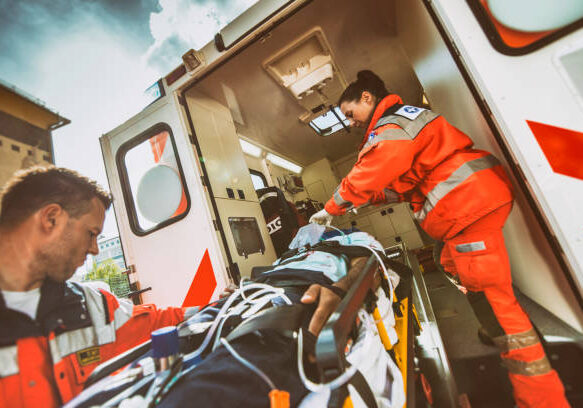 Paramedic team pushing stretcher with injured person towards ambulance.